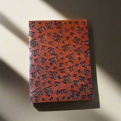 Brown leather notebook with embossed characters on a beige background