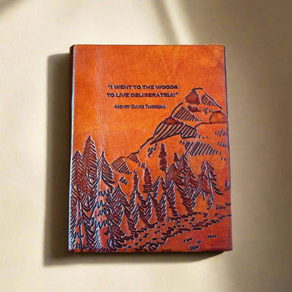 Leather-bound notebook with mountain and forest design on a beige background