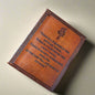 Brown leather-bound book with engraved text and design on a matching brown background