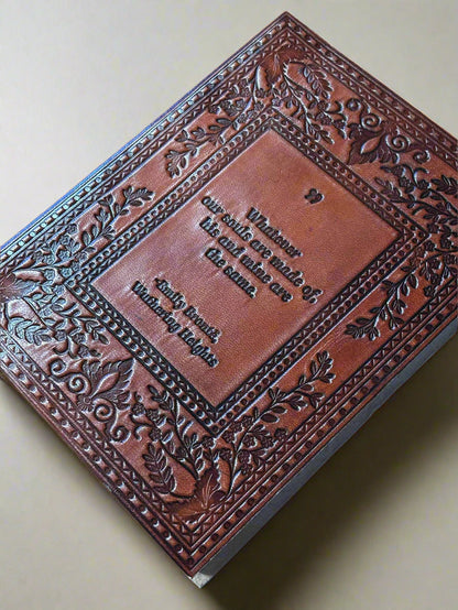 Brown leather-bound book with embossed design and text on a beige surface