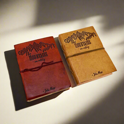 Two journals with leather covers, one in tan and one in brown, both with embossed text and artwork.