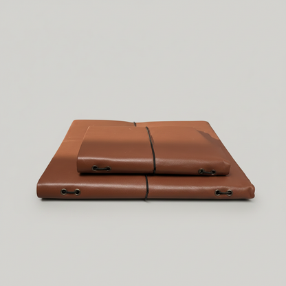 Two brown leather cases on a white surface with a blurred outdoor background