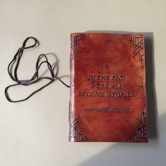 Brown leather-bound book with text and a lanyard on a light background